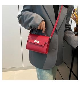 Model wearing a red pebble-textured mini handbag with metallic turn-lock and crossbody strap