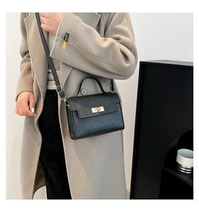 Black lychee leather mini kelly bag with gold clasp shown on a wool coat outfit