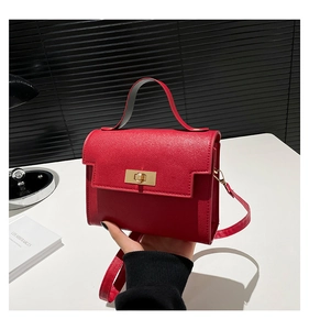 Detailed view of red litchi texture leather handbag with gold twist lock and top handle