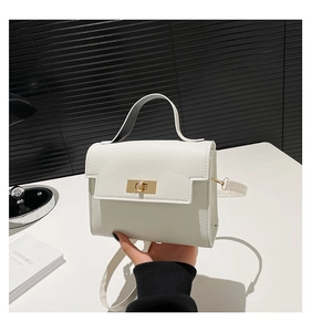 Detail of white textured crossbody bag with elegant golden twist lock and slim strap