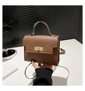 Detail of brown litchi pattern leather handbag with gold metal twist lock and handle
