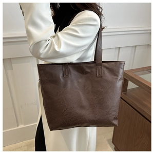 Close-up of a large dark brown tote bag with vintage cracked leather texture and thin straps