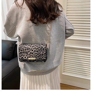 Detail of leopard print crossbody bag with gold chain strap on grey casual outfit