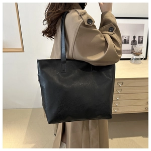 Vista detallada de un bolso tote grande de cuero negro con correas largas en modelo
