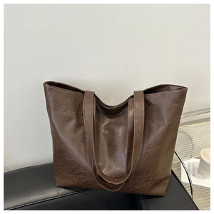 Detalle de bolso tote marrón oscuro con textura vintage de piel sintética en un banco