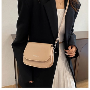 Detail view of light khaki crossbody bag with flap design and metal hook strap