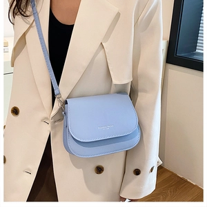 Detail of light blue saddle bag in matte leather featuring Fashion Trend logo and slim strap