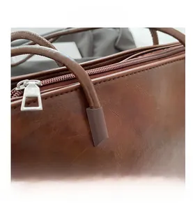 Close-up of brown leather tote bag with lychee texture and silver metal zipper detail