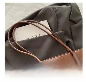 Detail showing high-quality dark brown leather texture and comfortable rolled handles