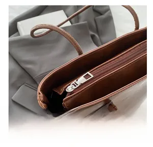 Detail view of smooth silver metal zipper on a dark brown leather tote bag