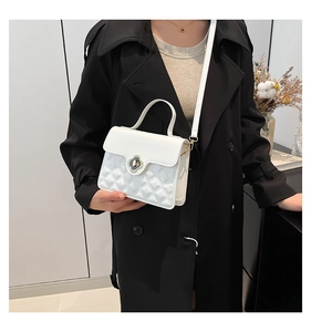 Close-up of a white textured crossbody bag with a floral metal clasp on a model