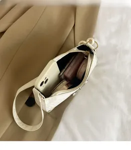 Detail view of the spacious interior of a white crescent shoulder bag with cosmetics