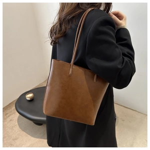 Close-up of minimalist dark brown leather tote bag showing fine texture and long straps