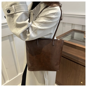 Detailed 45-degree side view of dark brown leather tote bag worn on shoulder