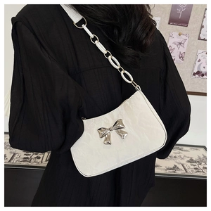 Close-up of white crescent bag with silver metal bow and textured cloud leather