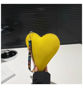 Detail of yellow heart-shaped leather bag with a colorful LOVE printed wrist strap