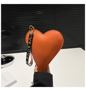 Close-up of orange heart-shaped coin purse with litchi texture and LOVE wrist strap
