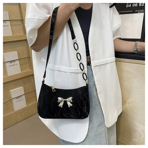 Detail of black pleated shoulder bag with silver bow and mixed chain leather strap