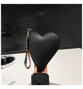 Detail of black heart-shaped handbag with pebbled leather and rainbow LOVE wrist strap