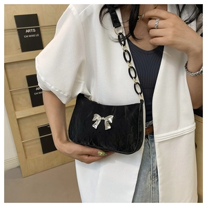 Detail of black crescent shoulder bag featuring ruched texture and silver bow buckle