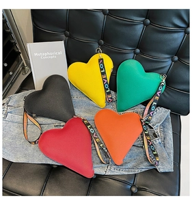 Top view of five heart-shaped wristlet bags in various colors on denim fabric