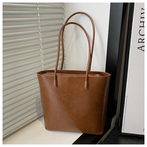 Detailed view of the brown leather tote bag showing high-quality texture and slim straps