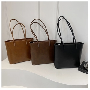 Minimalist leather tote bags in tan, brown and black shown on a display stand
