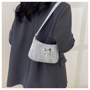 Detail of silver metallic pleated crescent bag with a decorative silver bow accessory