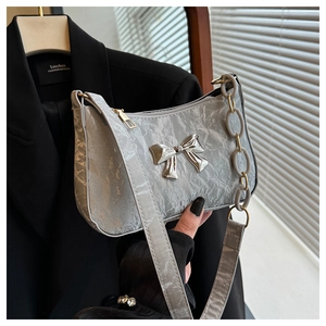 Silver crescent bag with pleated texture, metallic bow detail, and dual chain strap