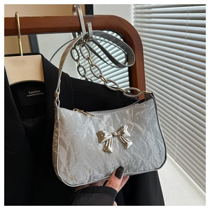Close-up of metallic silver crescent bag featuring a large bow and chain strap