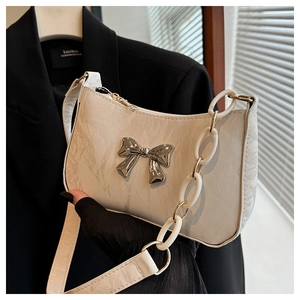 Detail of cream crescent bag with silver bow accent and chunky acrylic chain strap