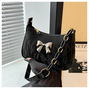 Detail of black pleated hobo bag with silver bow buckle and metallic chain strap