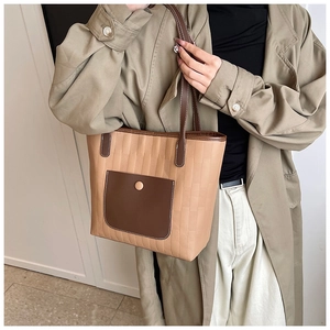 Close-up of khaki tote bag featuring vertical embossing and contrast brown front pocket