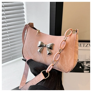 Detailed view of the pink crescent bag featuring silver bow accent and textured leather