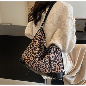 Detailed view of leopard print tote bag featuring black leather trim and bow knot detail