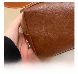 Macro shot of precise stitching and brown lychee grain leather texture on a lady handbag