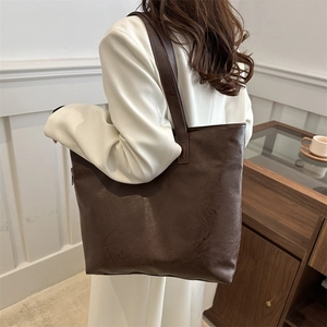 Bolso tote grande marrón retro llevado por una modelo en un estilo casual minimalista