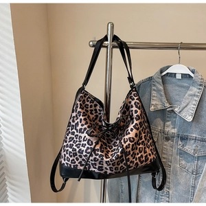 Detail of leopard print tote bag with black faux leather base and decorative bow accent