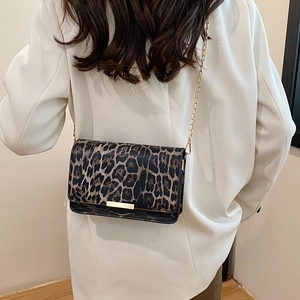 Chic leopard print crossbody bag with gold chain strap worn over a white blazer