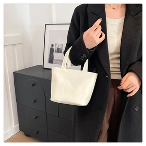Detail of a minimalist creamy white wrinkled leather mini tote bag with short handles