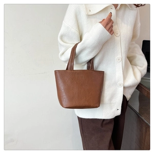 Side view of a brown vintage tote bag with soft pleated leather texture held by model