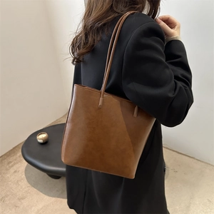 Brown leather tote bag for women showing a minimalist shoulder design on model