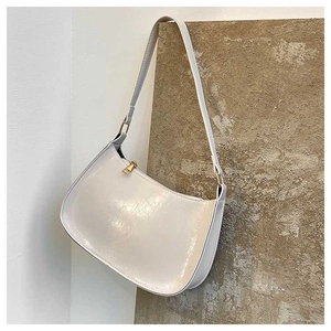 Detail of white half-moon hobo bag with glossy cracked texture and golden hardware