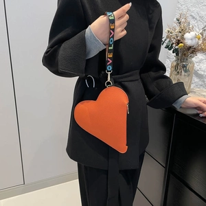 Bright orange heart-shaped leather handbag with LOVE printed strap on black coat