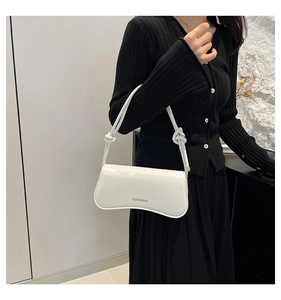Close-up of white leather underarm bag with curved base and twisted strap detail