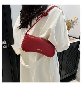 Primer plano de bolso de hombro rojo brillante con detalle decorativo de correa anudada