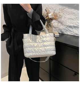 Close-up of metallic silver puffer tote bag featuring quilted texture and detachable strap