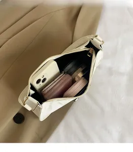 Top view of white textured shoulder bag showing spacious interior with phone and cosmetics