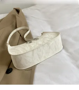 Detail of ivory underarm bag with silver butterfly buckle and marbled fabric texture