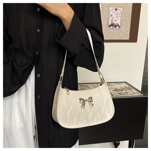 Detail of a creamy white glossy patent leather bag with a marble texture and silver bow